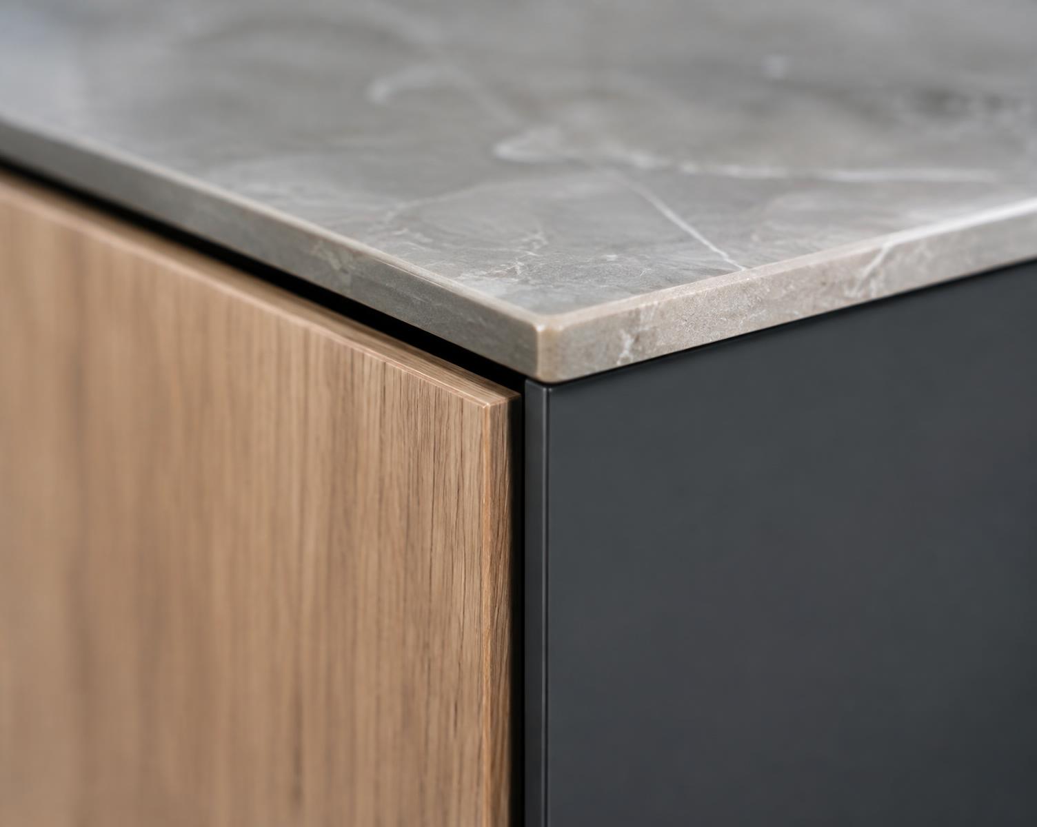 Concept image: oak door edge meeting a charcoal panel beneath a stone benchtop